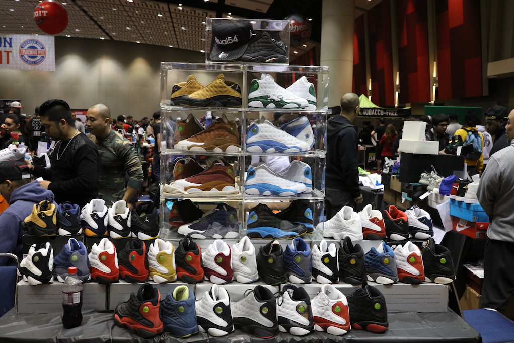 Group of sneakerheads at a Sneaker Con event, diverse crowd examining shoes and talking, vibrant and energetic atmosphere