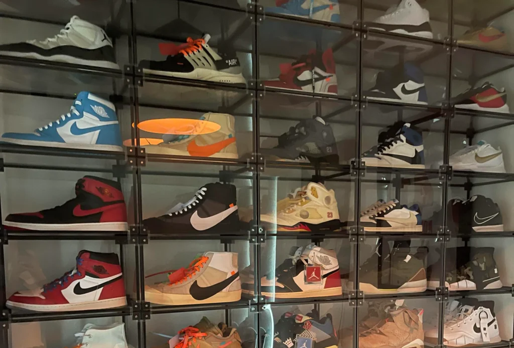Display case of rare sneakers under glass — collector vault / museum aesthetic with clean lighting